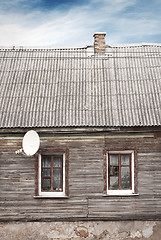 Image showing old house with a tiled roof and chimney, dramatic blue sky background