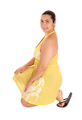 Image showing Pretty woman in yellow dress kneeling.