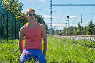 Image showing Young man in orange sitting on the green grass