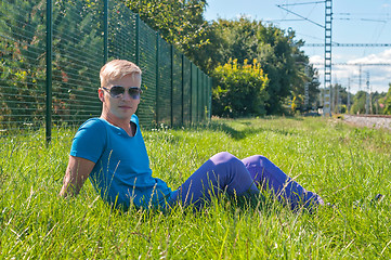 Image showing Young stylish man lying on the green grass