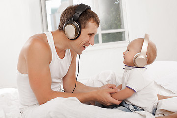 Image showing young father with his nine months old som on the bed at home