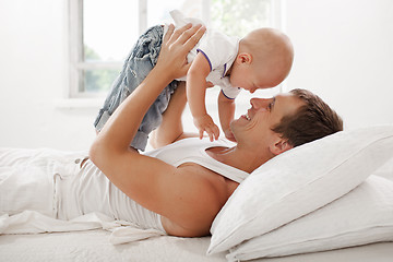 Image showing young father with his nine months old som on the bed at home