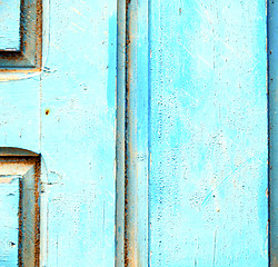 Image showing stripped paint in the blue wood door and rusty nail