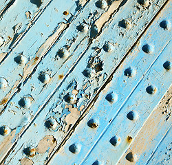 Image showing dirty stripped paint in the blue wood door and rusty nail