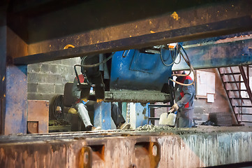 Image showing Workers operates machine with trowels