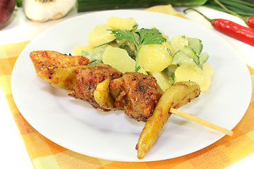 Image showing Potato-cucumber salad with fire skewers and parsley