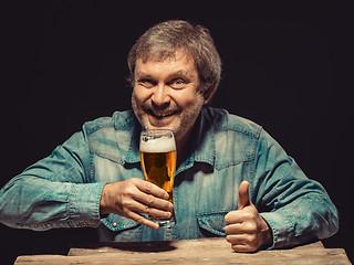 Image showing The smiling man in denim shirt with glass of beer