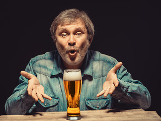 Image showing The spellbound man in denim shirt with glass of beer