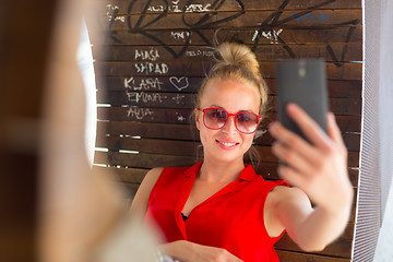 Image showing Young cheerful lady taking selfie.