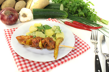 Image showing Potato-cucumber salad with fire skewers and parsley