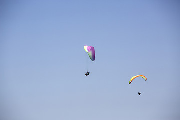 Image showing Colorful paragliders with blue sky