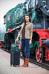 Image showing adult woman traveler with a suitcase near the vintage steam loco