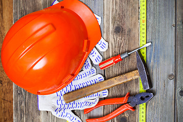 Image showing aged hammer, pliers, screwdriver, tape measure, a bright helmet 