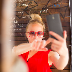 Image showing Young cheerful lady taking selfie.