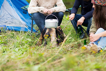 Image showing close up of friends cooking food in dixie at camp 