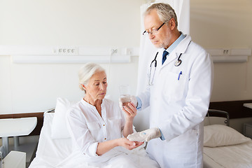 Image showing doctor giving medicine to senior woman at hospital