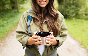 Image showing smiling young woman with cup and backpack hiking