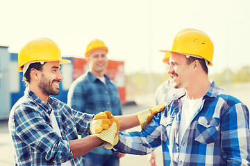 Image showing group of smiling builders in hardhats outdoors