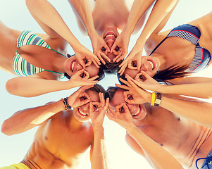 Image showing smiling friends in circle on summer beach