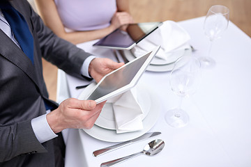 Image showing close up of couple with tablet pc at restaurant