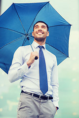 Image showing young smiling businessman with umbrella outdoors