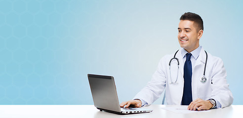 Image showing smiling male doctor with laptop sitting at table