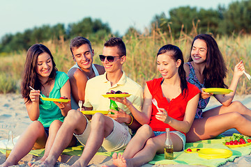 Image showing smiling friends sitting on summer beach