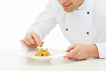 Image showing close up of happy male chef cook decorating dish