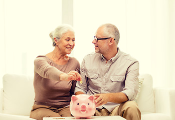 Image showing senior couple with money and piggy bank at home