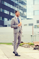 Image showing young serious businessman with paper cup outdoors