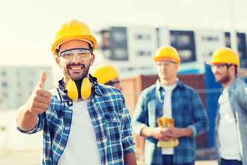 Image showing group of smiling builders in hardhats outdoors