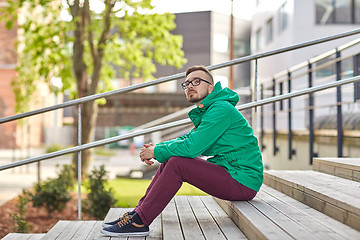 Image showing happy young hipster man sitting on stairs in city