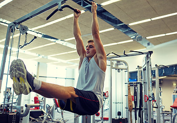 Image showing man flexing abdominal muscles on pull-up bar