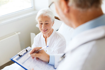 Image showing senior woman and doctor with clipboard at hospital