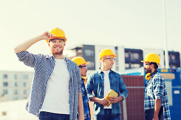 Image showing group of smiling builders in hardhats outdoors