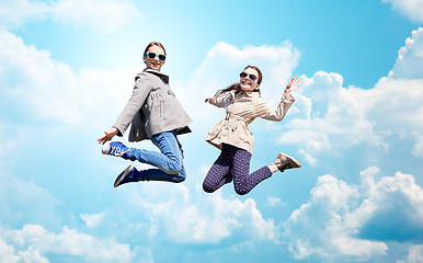 Image showing happy little girls jumping high over blue sky