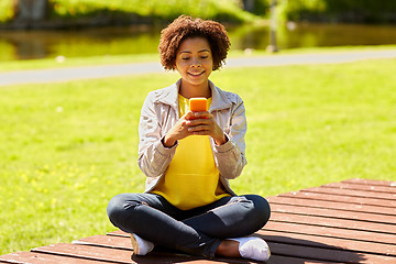 Image showing happy african young woman messaging on smartphone