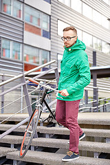 Image showing young hipster man carrying fixed gear bike in city