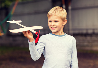 Image showing smiling little boy holding a wooden airplane model