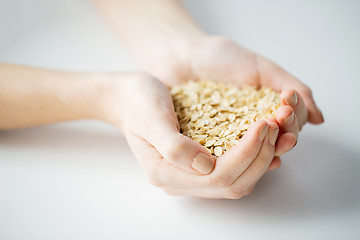 Image showing close up of woman hands holding oatmeal flakes