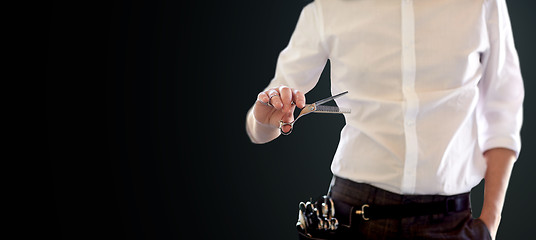 Image showing close up of male stylist with scissors over black