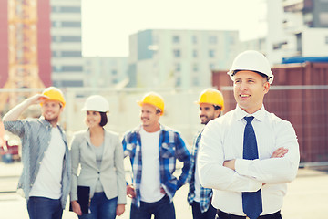 Image showing group of smiling builders in hardhats outdoors