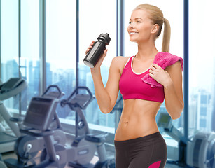 Image showing happy woman drinking water from bottle in gym