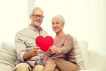 Image showing happy senior couple with red heart shape at home