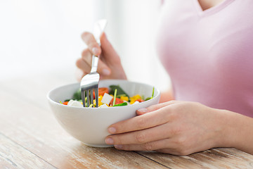 Image showing close up of young woman eating salad at home