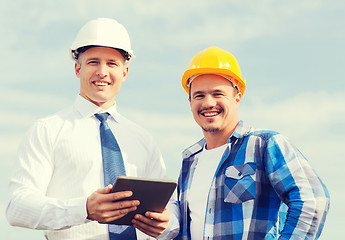 Image showing smiling builders in hardhats with tablet pc