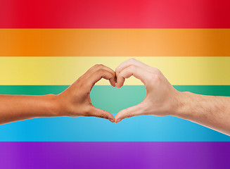 Image showing human hands showing heart shape over rainbow