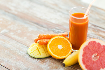 Image showing close up of fresh juice glass and fruits on table