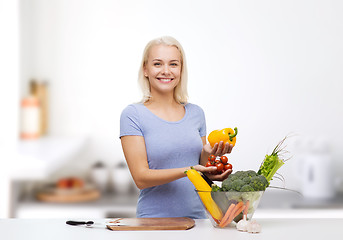 Image showing smiling young woman cooking vegetables in kitchen 