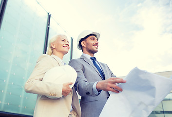 Image showing smiling businessmen with blueprint and helmets